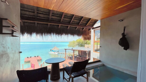 A balcony with a view of the sea, a table, and chairs.