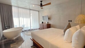 A modern bedroom with a large bed, a freestanding bathtub, a ceiling fan, and a round rug. - Amainah Bacalar (Bacalar)