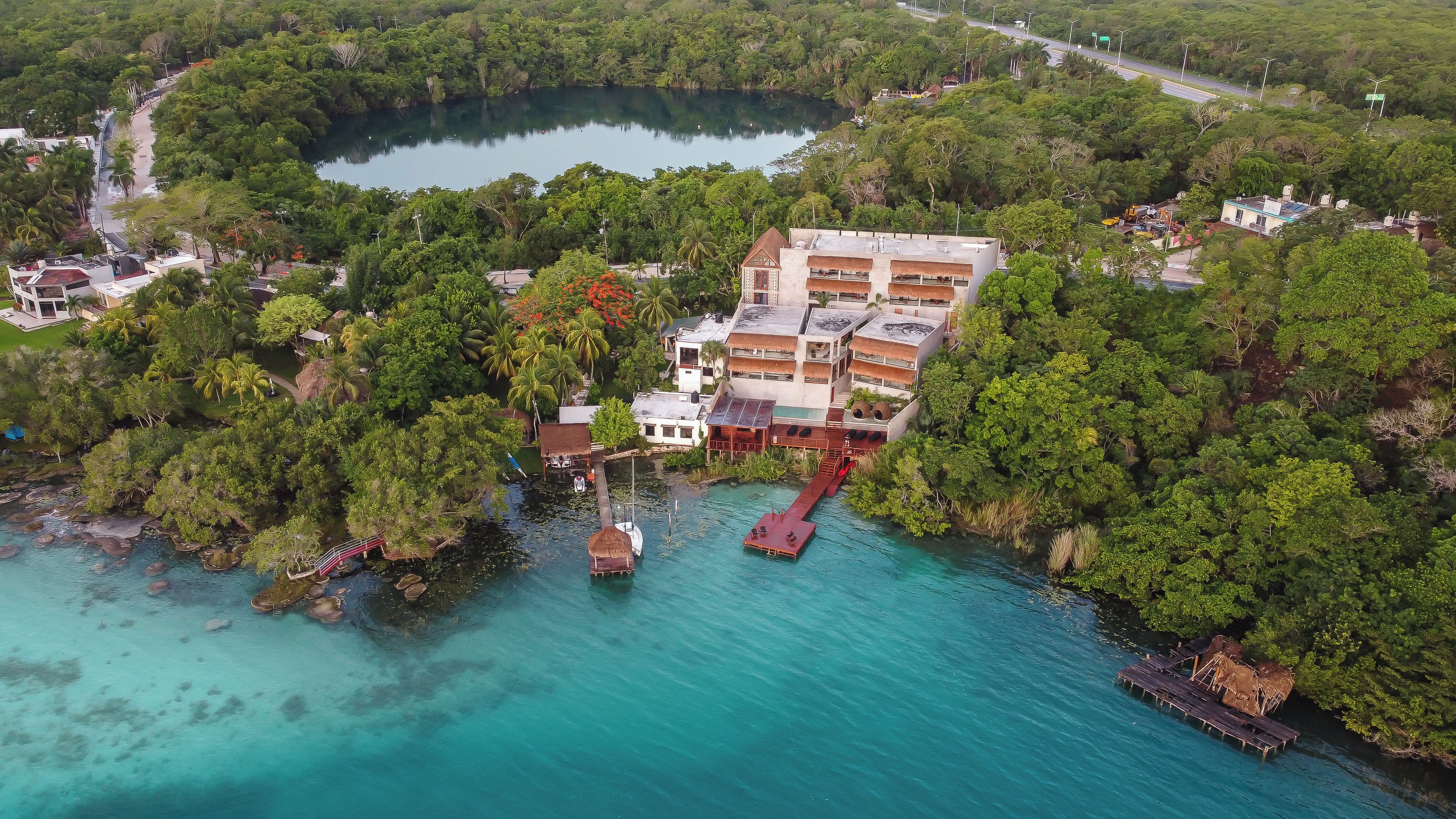 Vista aérea de um resort costeiro com um prédio grande, um píer e águas turquesa cristalinas.