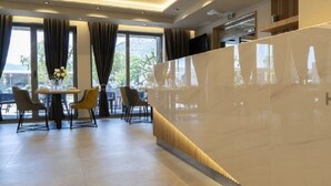 Zona de recepción de un hotel con diseño moderno, una mesa de recepción y un área de estar con sillas y una mesa.