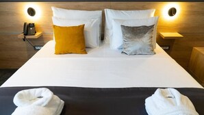 Una habitación de hotel con cama, dos lámparas de noche, teléfono y dos toallas.