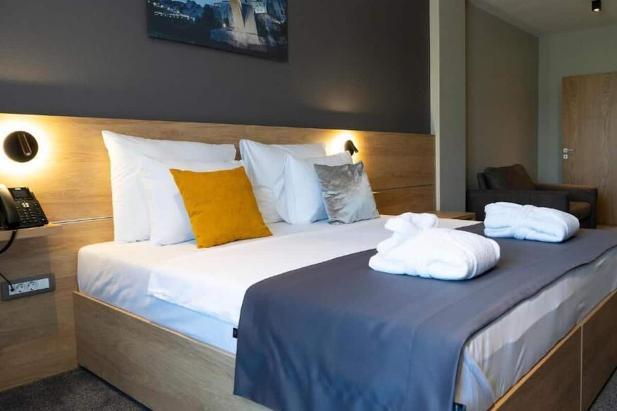 Quarto de hotel com cama, mesa de cabeceira e telefone.