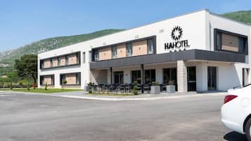 Un hotel moderno con techo plano, un logotipo destacado y una zona de estar exterior cubierta.