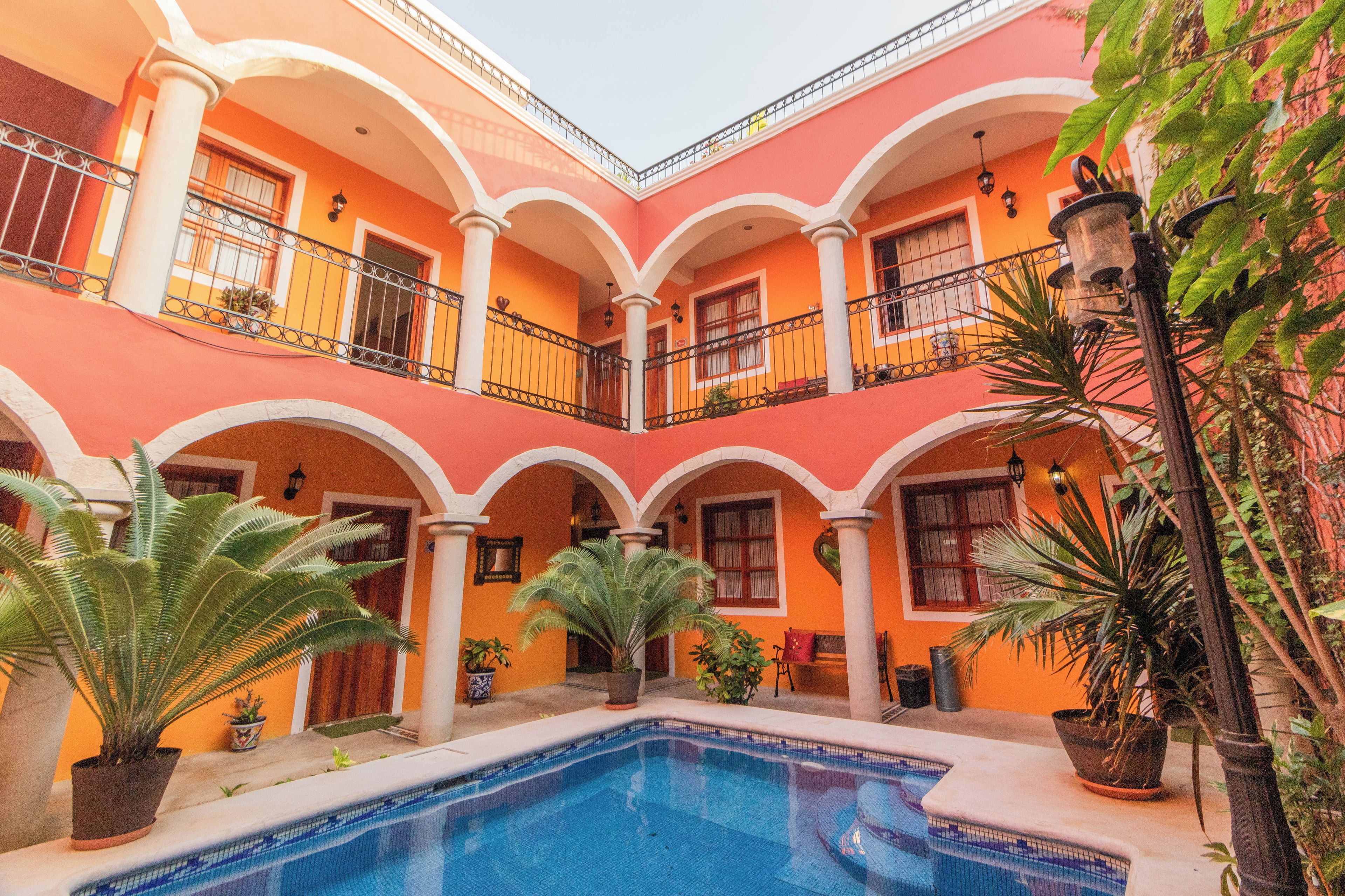 Une cour avec une piscine, des plantes en pot et un bâtiment doté de balcons.