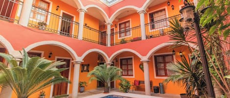 A courtyard with a swimming pool, potted plants, and a building with balconies.
