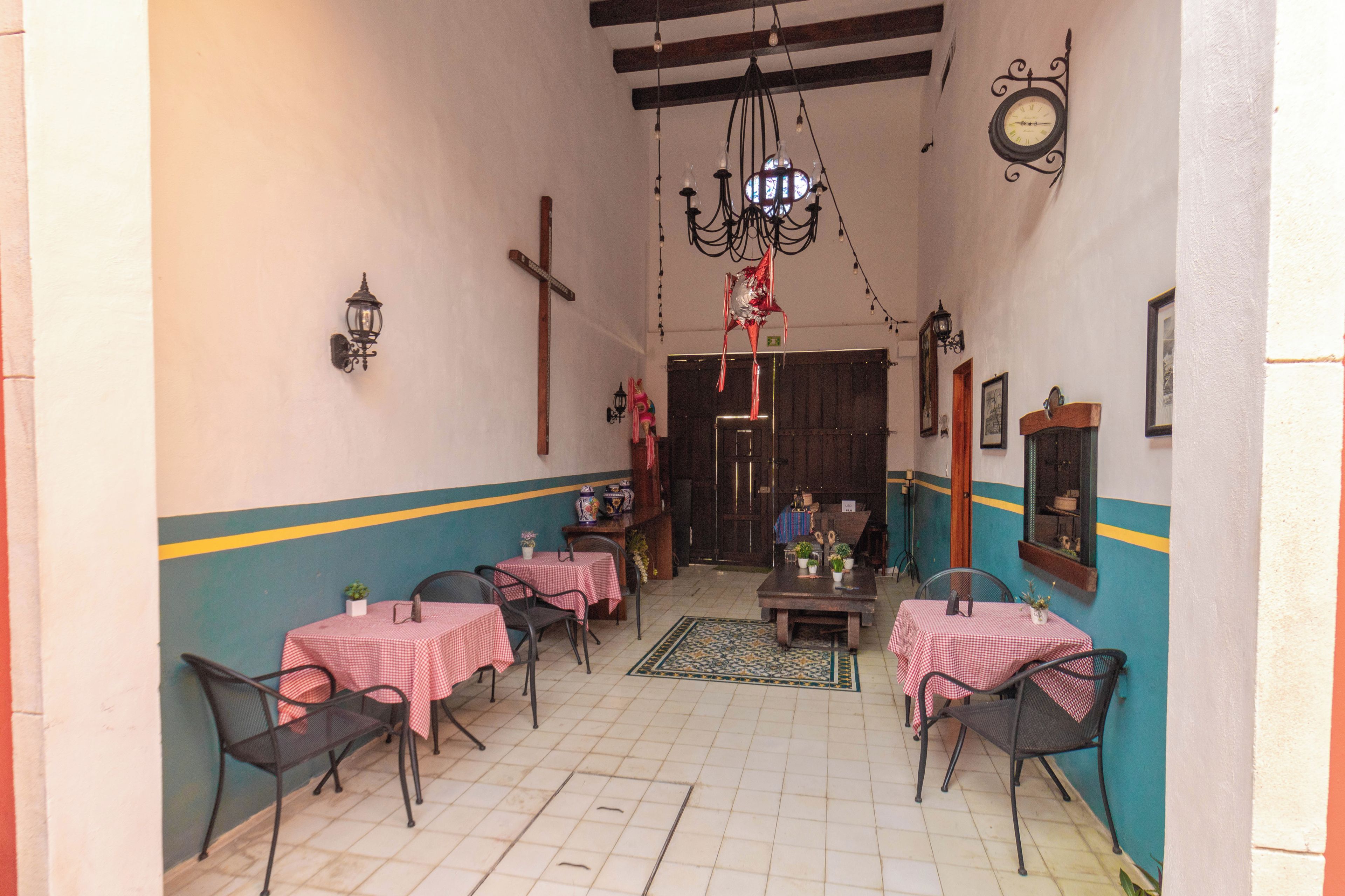 Un comedor con mesas y sillas, una araña y un reloj de pared.