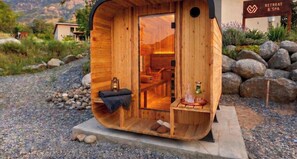 A wooden sauna structure with a bench, a small table with a bottle and glass, and a view of a mountainous landscape. - Sequoia Park Retreat: Patio, Fire Pit, Game Area (Three Rivers)