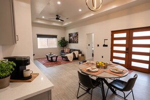A modern living space with a dining area, a sofa, a coffee table, and a dining table set for four. - Sequoia Park Retreat: Patio, Fire Pit, Game Area (Three Rivers)