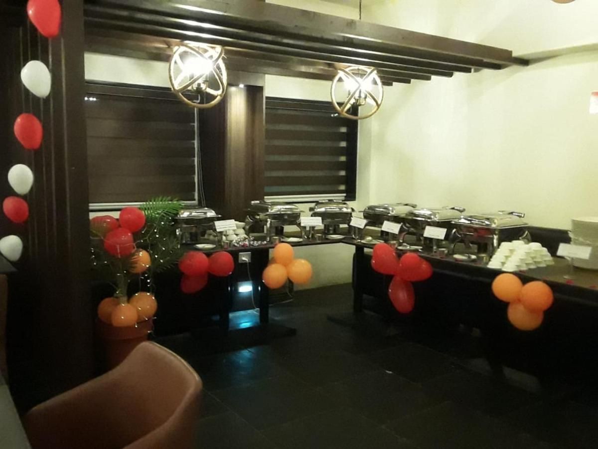 A room with tables set up for a buffet, decorated with balloons, and a Christmas tree with ornaments.