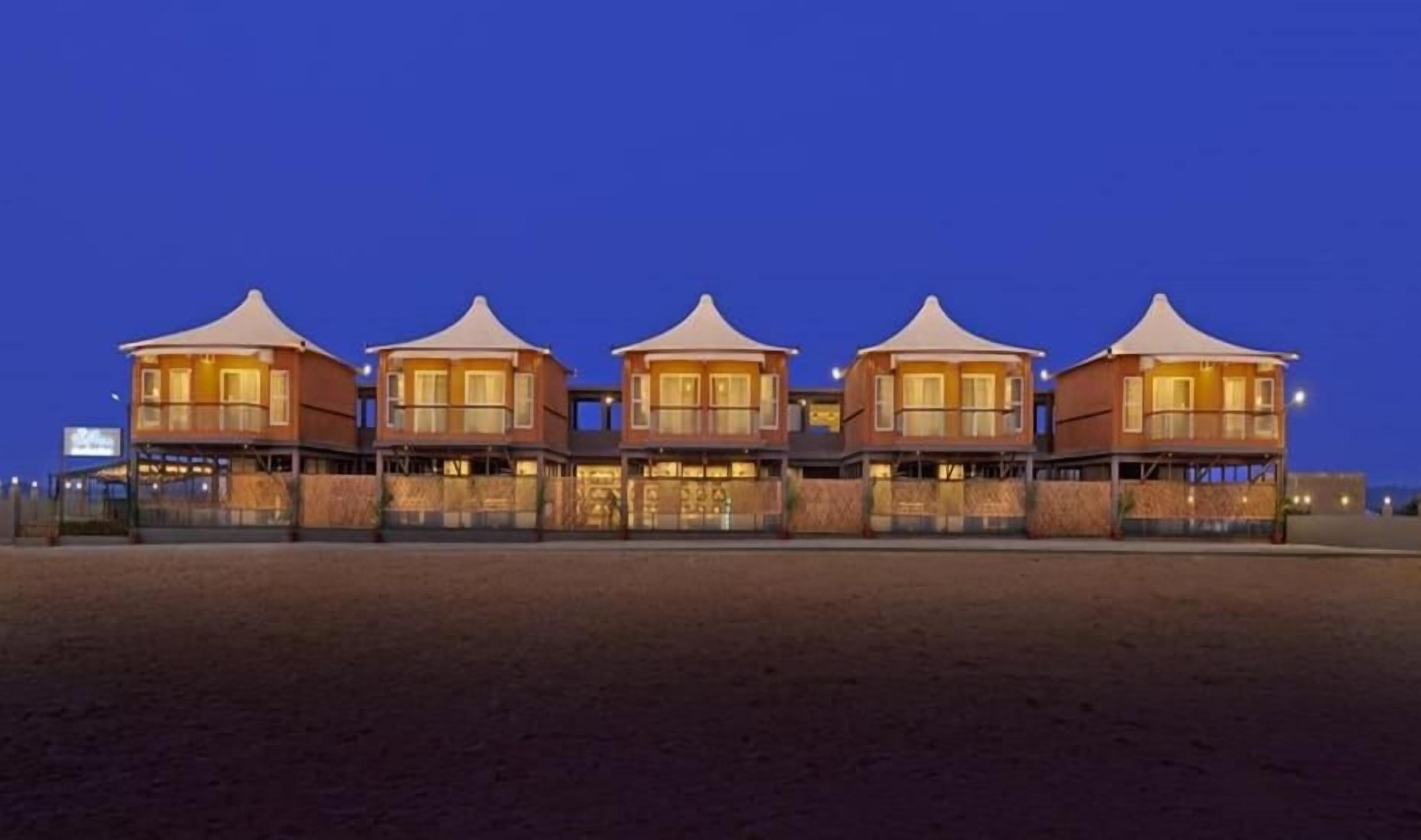 A beachfront hotel with multiple connected buildings, each featuring a curved roof and a balcony.