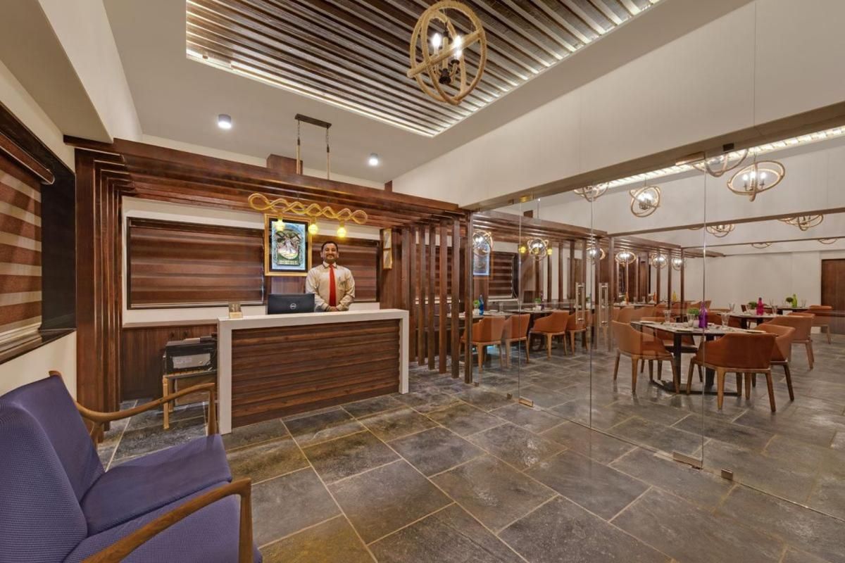 A hotel lobby with a reception desk, seating area, and modern lighting fixtures.