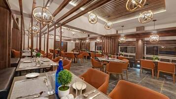 A restaurant with multiple dining tables, chairs, and hanging spherical light fixtures.