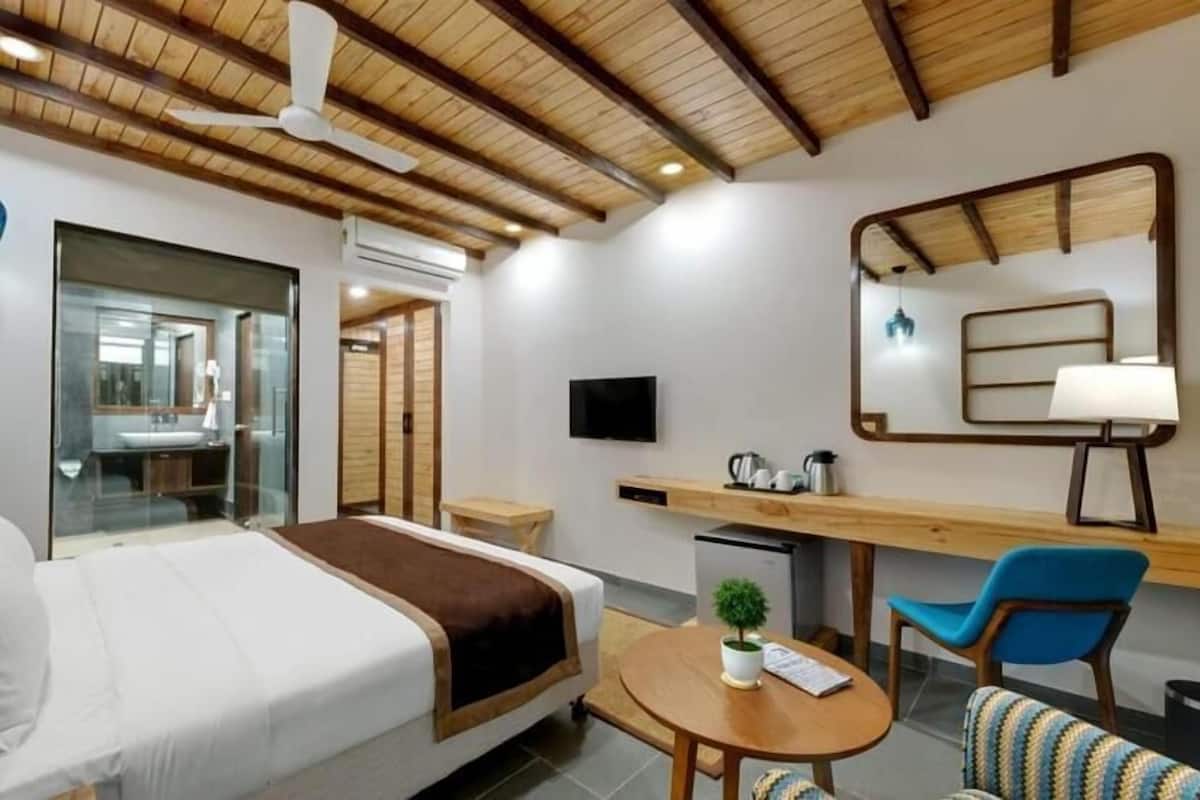 A hotel room with a bed, a desk, a chair, a television, and a mirror.
