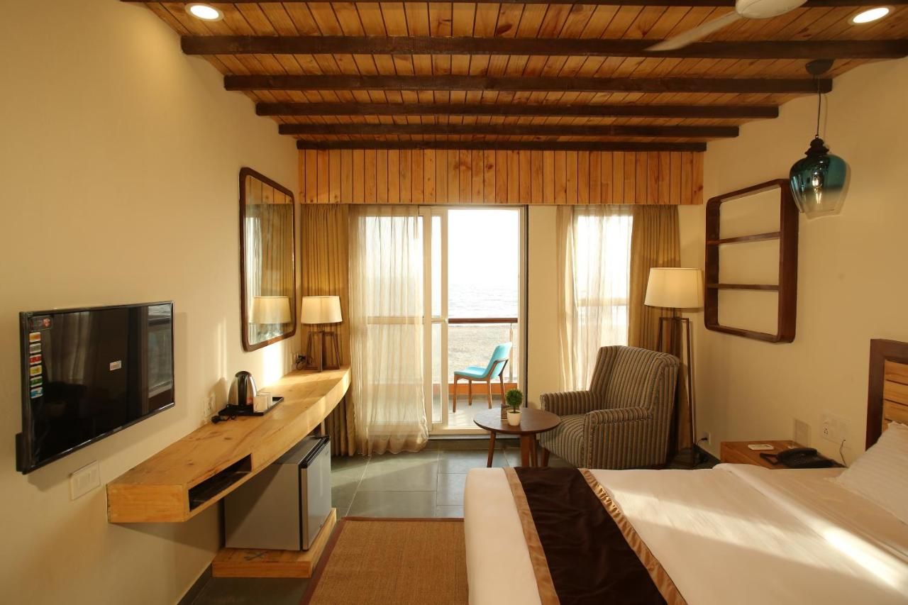 A hotel room with a bed, a desk, a chair, a TV, and a balcony with a view.