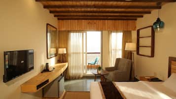 A hotel room with a bed, a desk, a chair, a TV, and a balcony with a view.