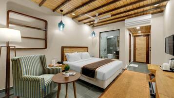 A hotel room with a bed, a chair, a small table, a desk, and a TV.
