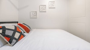 Une chambre d’hôtel avec un lit, des oreillers et trois œuvres d’art encadrées accrochées au mur.