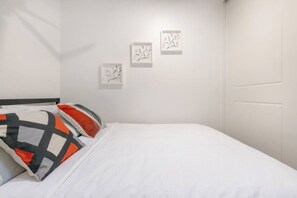 A hotel room with a bed, pillows, and three framed artworks on the wall.