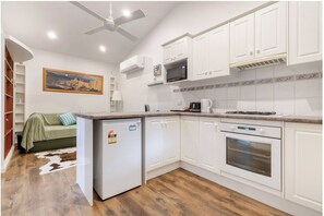 A modern kitchen with white cabinets, a microwave, an oven, and a refrigerator.