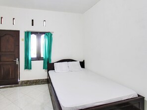 Een slaapkamer met een bed, een raam met gordijnen, een deur en een betegelde vloer.