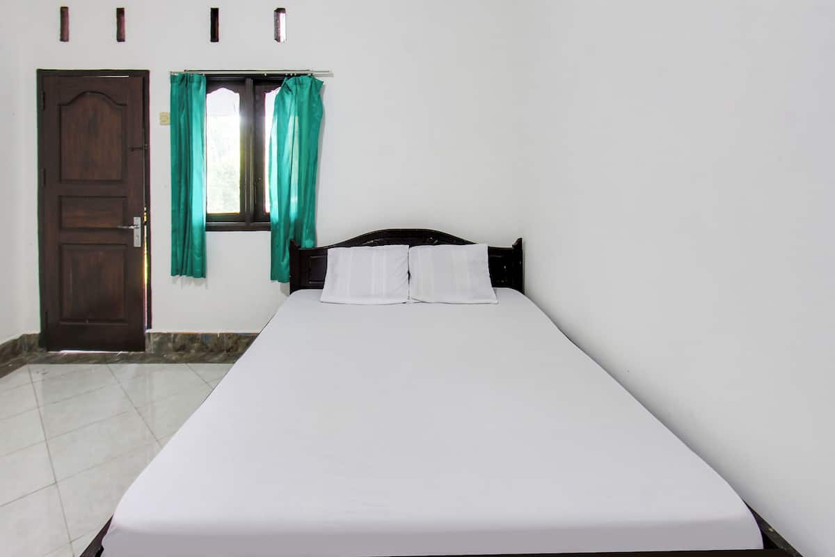 Uma cama de solteiro com lençóis brancos, cabeceira de madeira e janela com cortinas verdes.