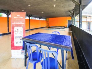 Een binnenruimte met een blauwe tafel en stoelen, een rood bord en oranje muren.
