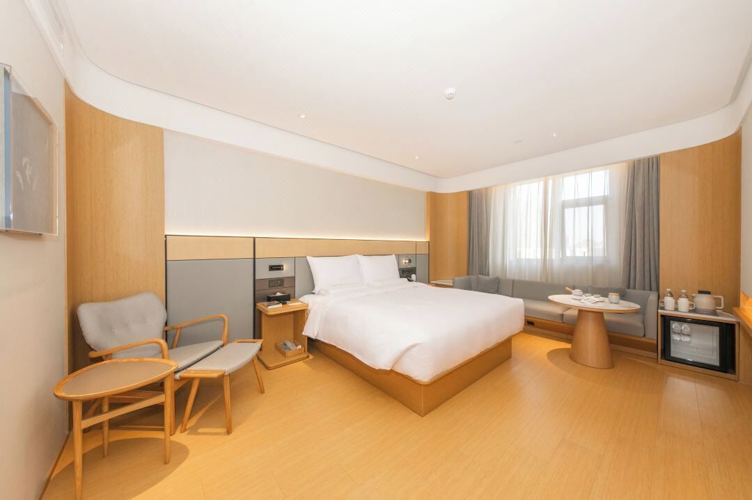 Una habitación de hotel moderna con una cama, un escritorio, una silla, una mesita y un televisor.