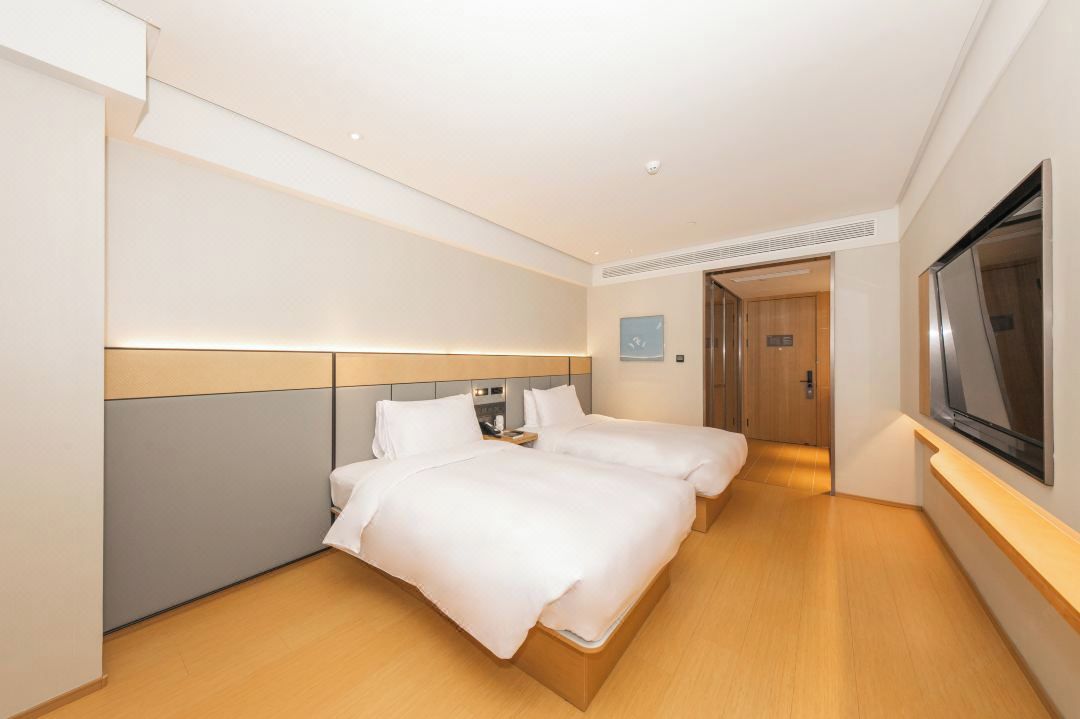A hotel room with two beds, a television, and a door leading to a bathroom.