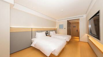 A hotel room with two beds, a television, and a door leading to a bathroom.