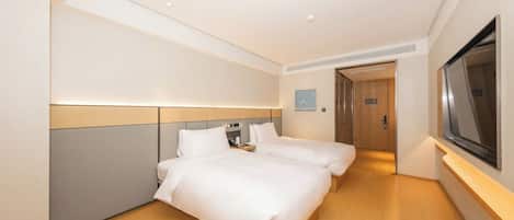 A hotel room with two beds, a television, and a door leading to a bathroom.