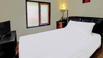 A hotel room with a bed, a TV, a nightstand, a lamp, a window, and a wall art piece.