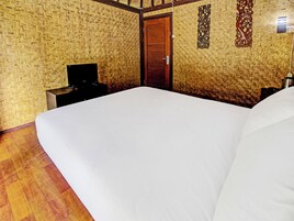 Una habitación con una cama grande, una puerta de madera, un escritorio con una silla y una pared con diseño tejido.