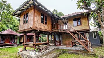 Ein zweigeschossiges Holzhaus mit Balkon, Treppe und einer kleinen Veranda.