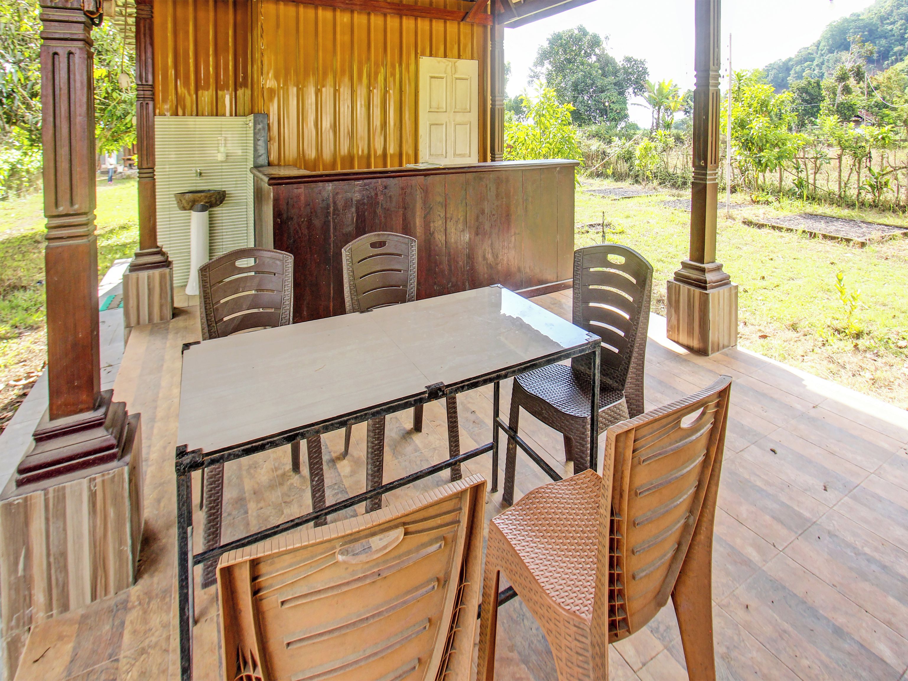 An outdoor dining area with a table and chairs, a wooden door, and a view of the surrounding landscape.