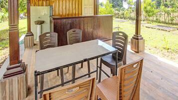 An outdoor dining area with a table and chairs, a wooden door, and a view of the surrounding landscape.