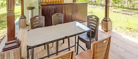 Un área de comedor al aire libre con una mesa y sillas, una puerta de madera y vistas del paisaje circundante.