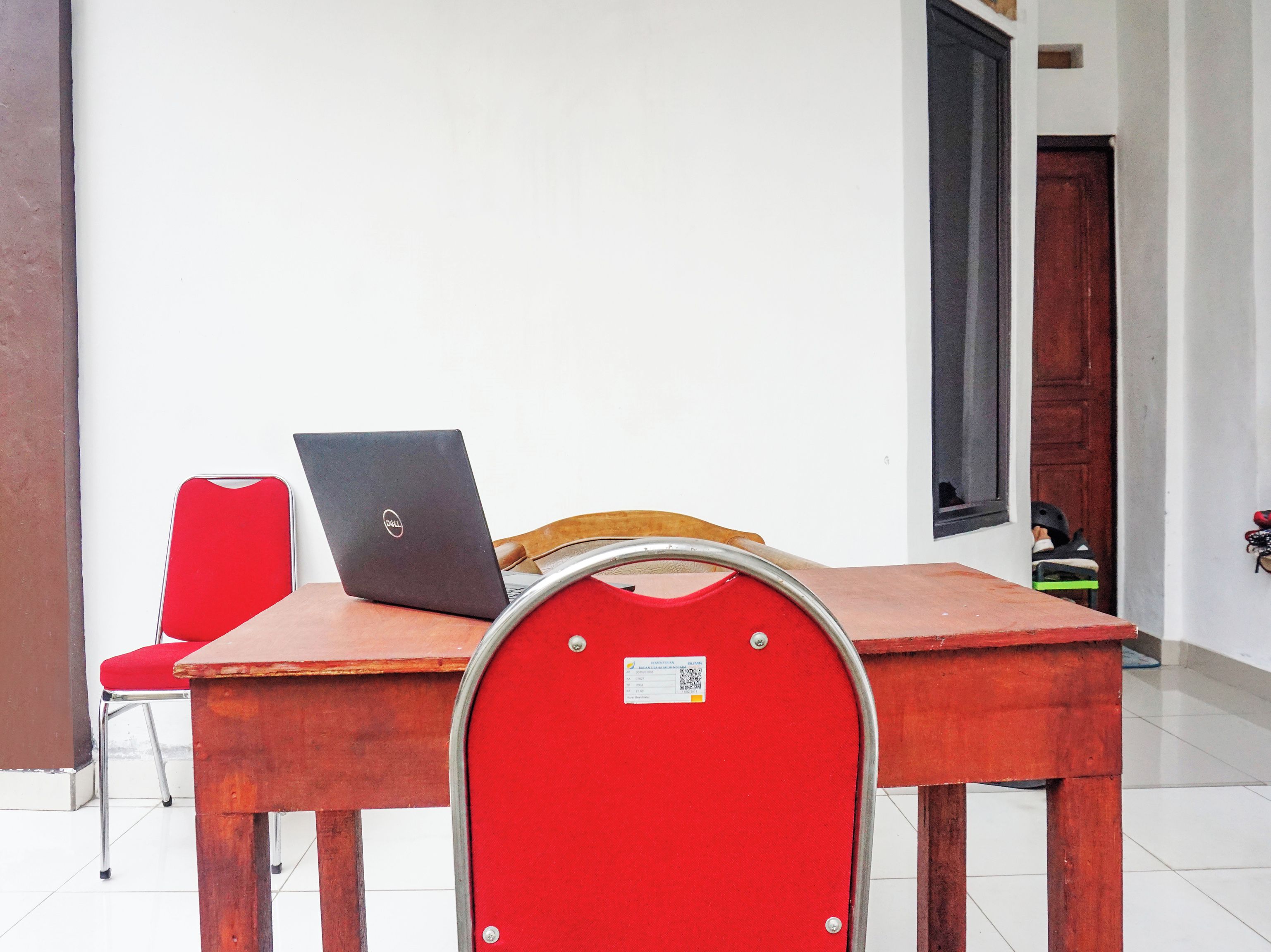 Una habitación con una mesa de madera, una silla roja y un ordenador portátil.