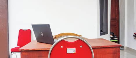 A room with a wooden table, a red chair, and a laptop.