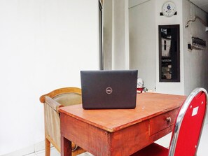 A wooden table with a laptop, a chair, and a red cabinet. - Oyo 91654 Bintang Residence (Jakarta)