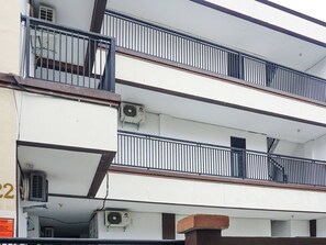 Un edificio a più piani con balconi, condizionatori d'aria e un cartello visibile con scritte.