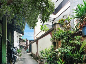 A narrow alleyway with a parked motorcycle, potted plants, and a building with a balcony. - Oyo 91654 Bintang Residence (Jakarta)