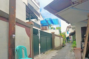 A narrow alleyway with a metal gate, a blue tarp, and a green chair. - Oyo 91654 Bintang Residence (Jakarta)