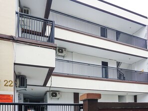 Un edificio de varios pisos con balcones y unidades de aire acondicionado.