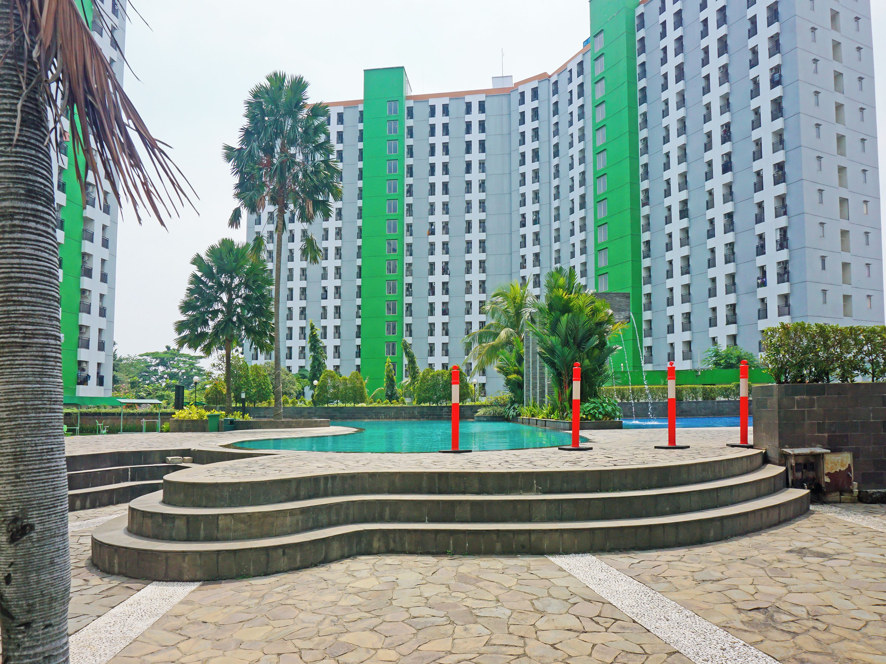 A multi-story residential building with a swimming pool and landscaped garden.