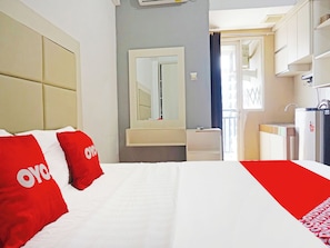 Quarto de hotel com cama, mesa de cabeceira, espelho, pia pequena e guarda-roupa.