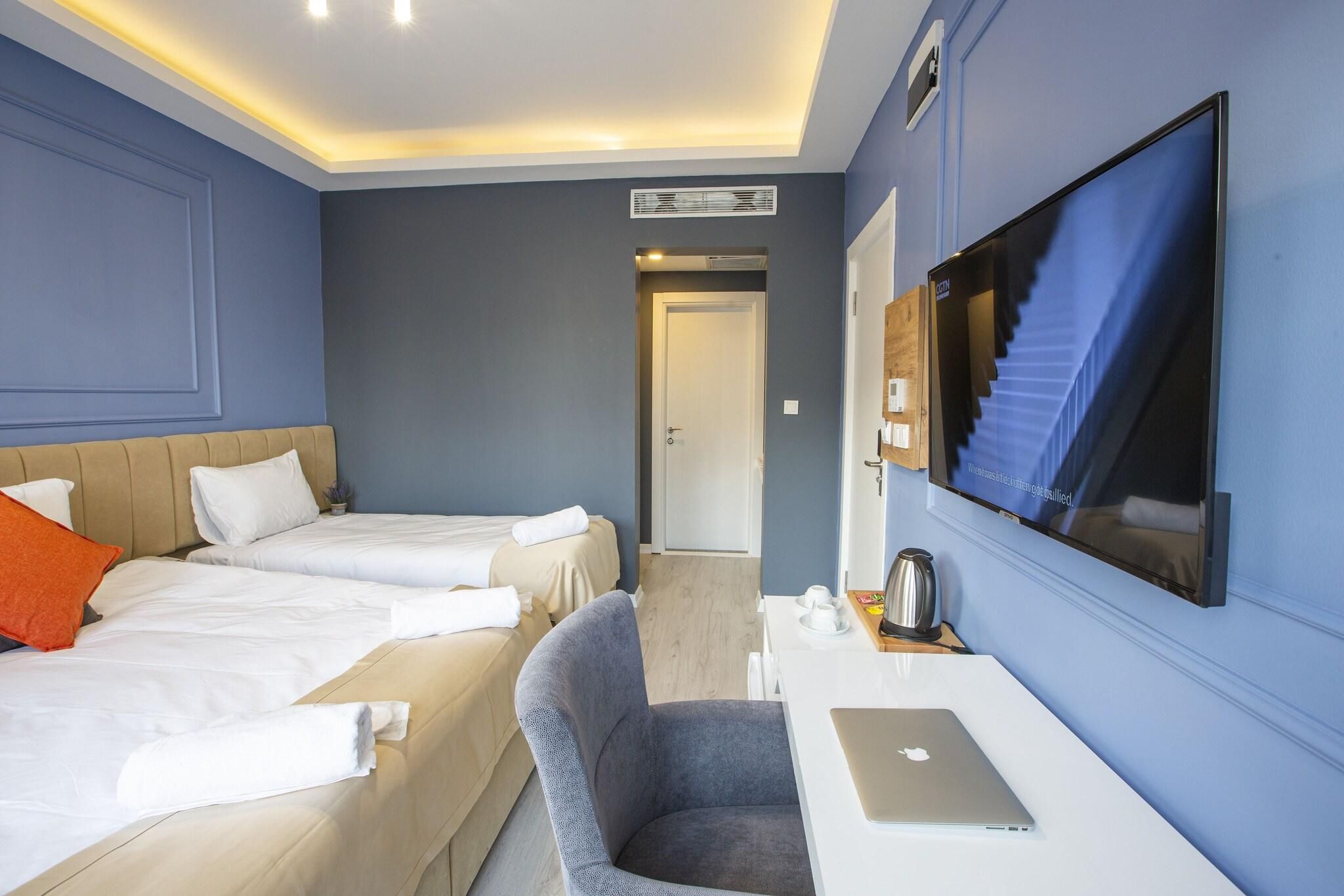 Une chambre d’hôtel avec deux lits, un bureau avec un ordinateur portable, une télévision et une machine à café.