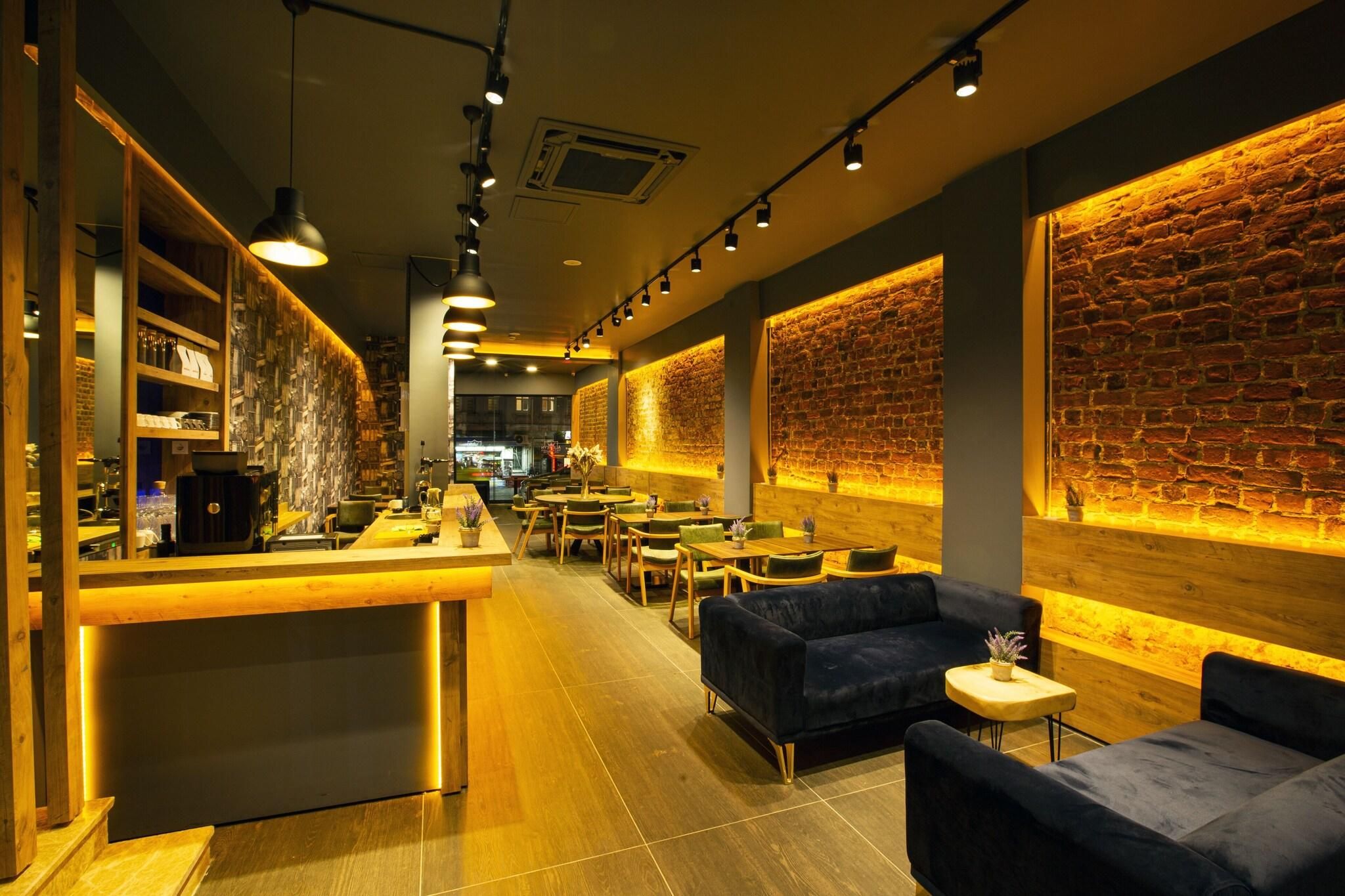 A modern interior with a bar area, seating, and exposed brick walls.
