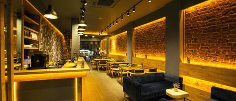 A modern interior with a bar area, seating, and exposed brick walls.