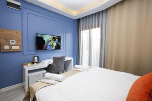 A hotel room with a bed, a desk, a television, a coffee maker, and a window with curtains. - Taksim Leon S Hotel (Istanbul)