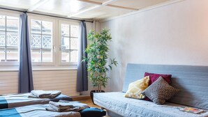 Ett hotellrum med en säng, en soffa, en krukväxt och ett fönster med gardiner.